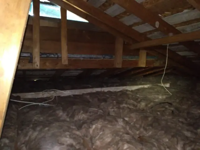 Attic with old, compressed blown-in insulation before cleanup