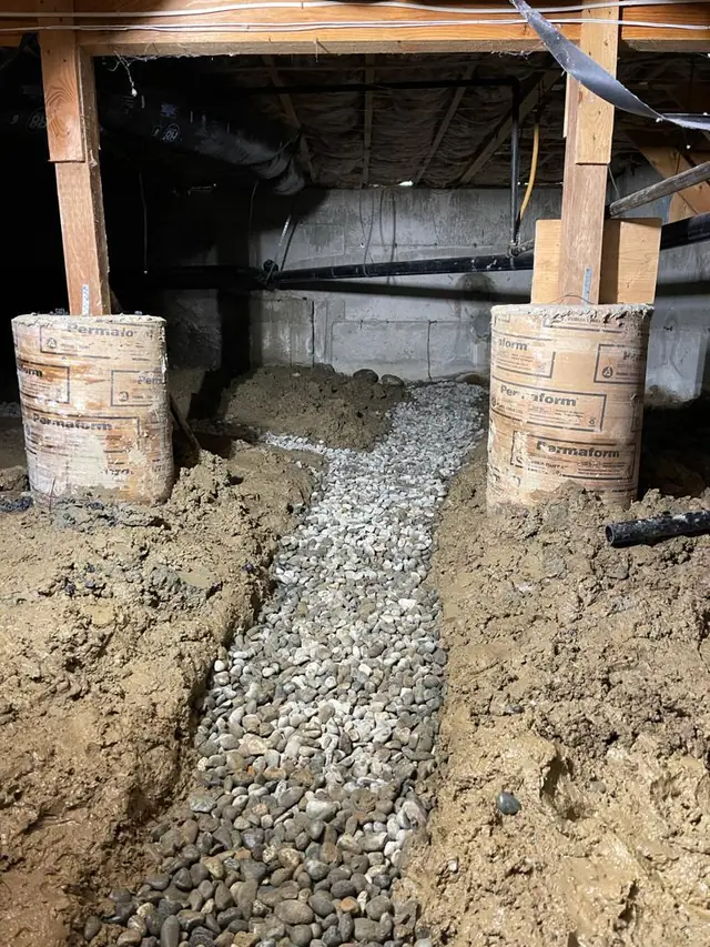 Gravel drainage trench dug through crawl space soil