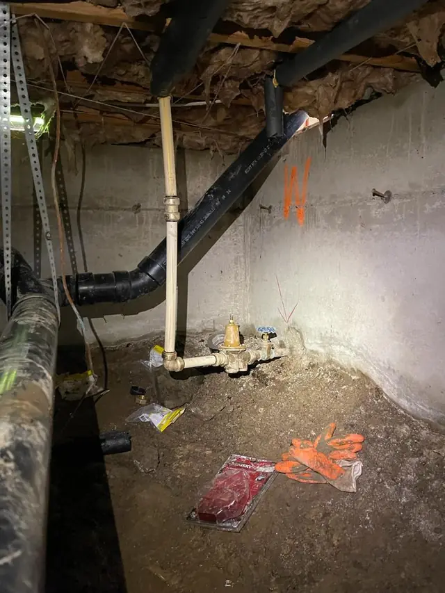 Sump pump discharge plumbing along the foundation wall