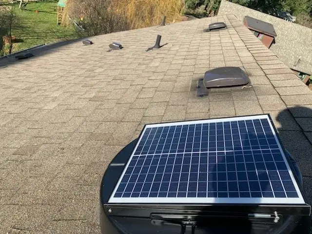 Solar-powered attic fan installed on a shingle roof