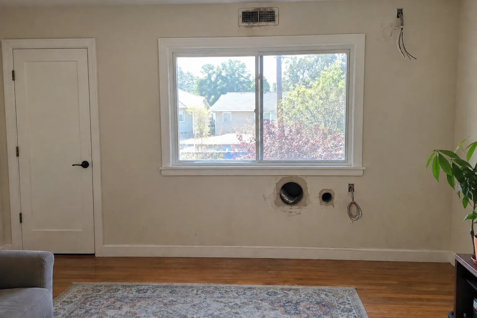Before: Living room wall with old line-set holes and no cooling.