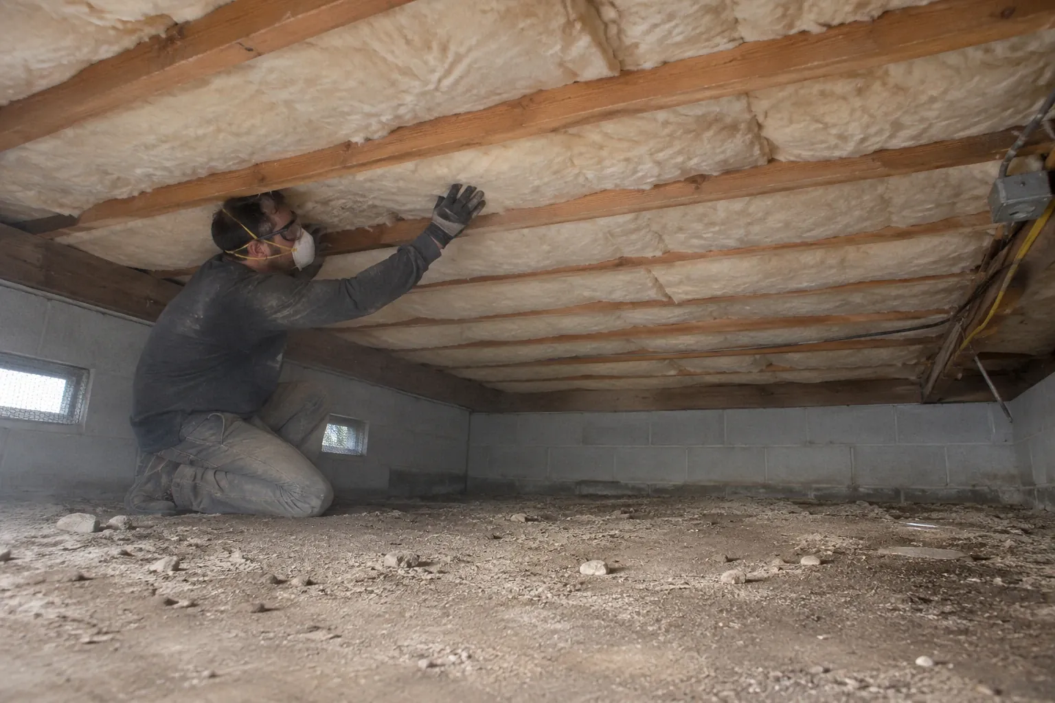 After: Fitting new insulation between the floor joists.