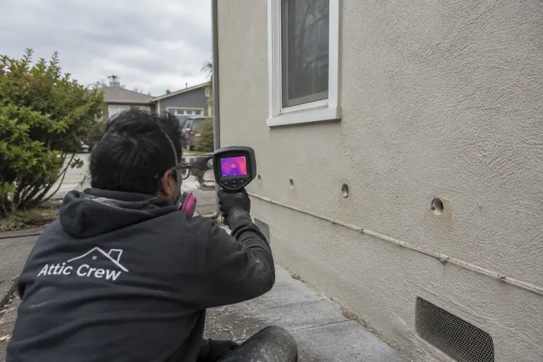 Checking fill coverage with a thermal camera after insulating a stucco wall.